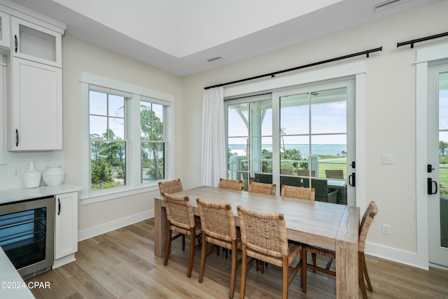 dining area with light hardwood / wood-style flooring, a healthy amount of sunlight, and beverage cooler