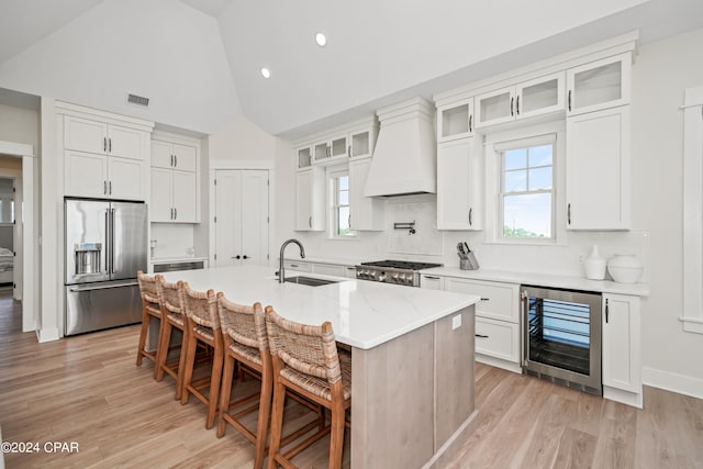 kitchen featuring sink, custom exhaust hood, an island with sink, appliances with stainless steel finishes, and wine cooler