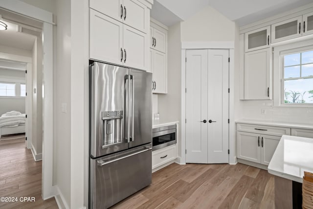 kitchen featuring white cabinetry, stainless steel appliances, light hardwood / wood-style floors, and tasteful backsplash