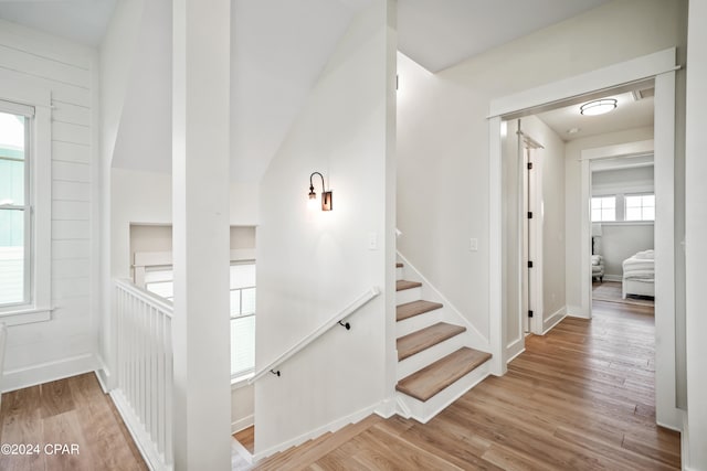 staircase with wood walls and wood-type flooring