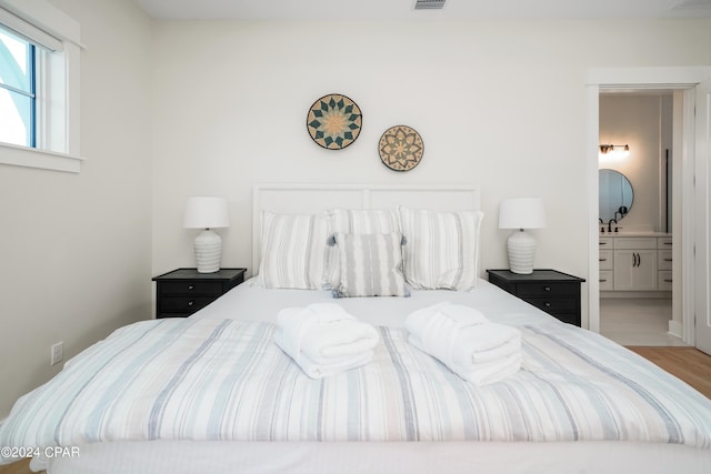 bedroom featuring light wood-type flooring and ensuite bathroom