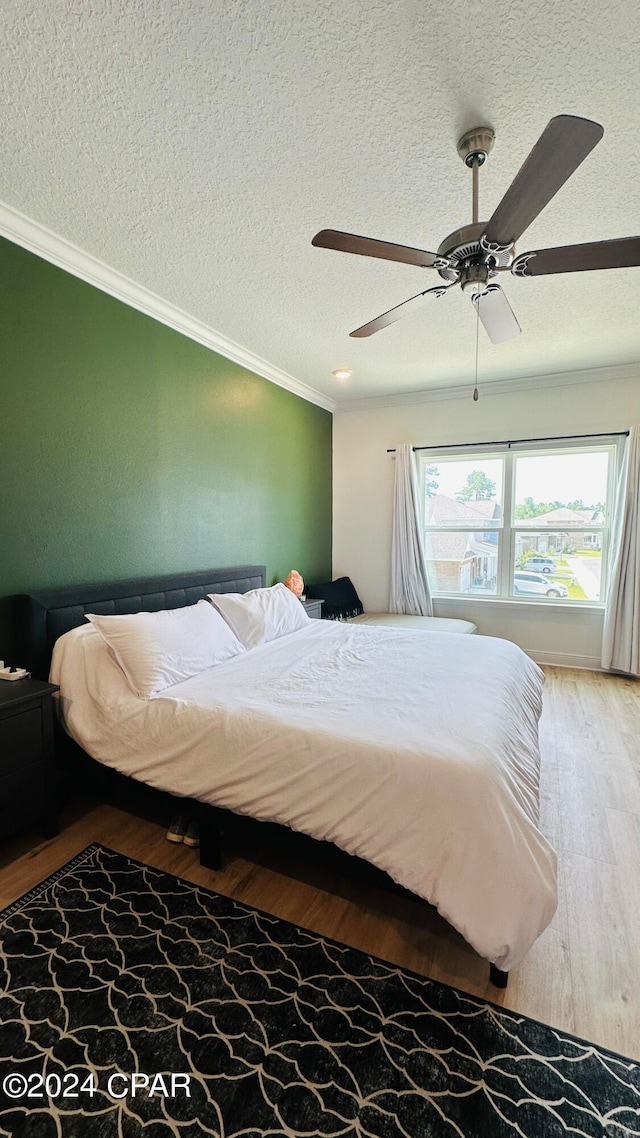 bedroom with ornamental molding, ceiling fan, hardwood / wood-style floors, and a textured ceiling