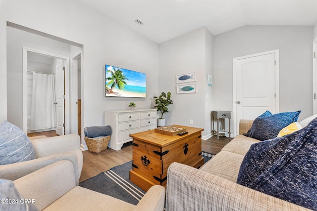 living room with visible vents, vaulted ceiling, and wood finished floors