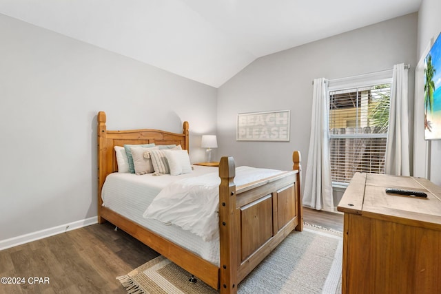 bedroom with lofted ceiling, wood finished floors, and baseboards