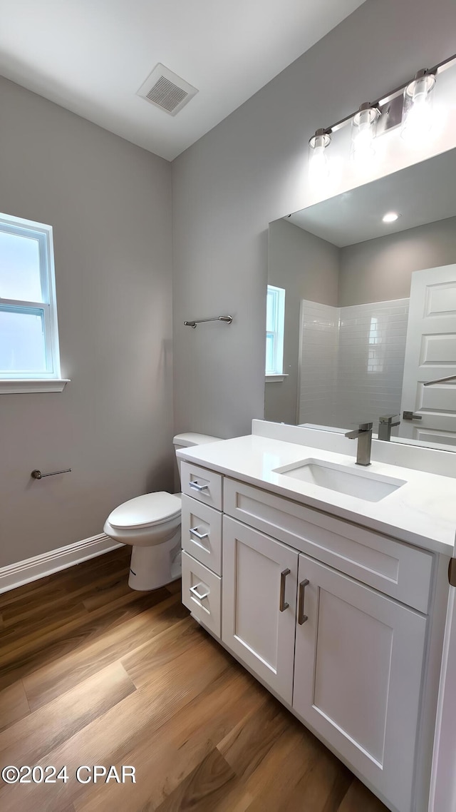 bathroom with hardwood / wood-style floors, plenty of natural light, toilet, and a shower