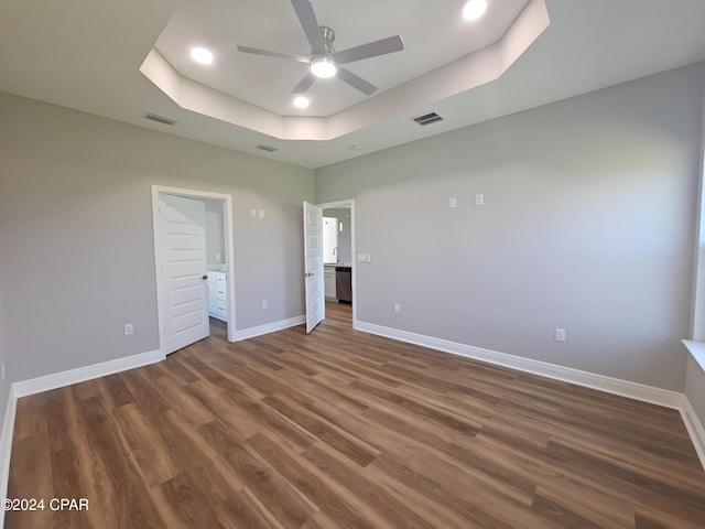 unfurnished bedroom featuring a raised ceiling, ceiling fan, and dark wood-type flooring