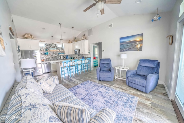 living room with light hardwood / wood-style flooring, lofted ceiling, and ceiling fan