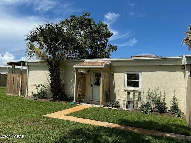 view of front of house with a front yard, fence, and stucco siding