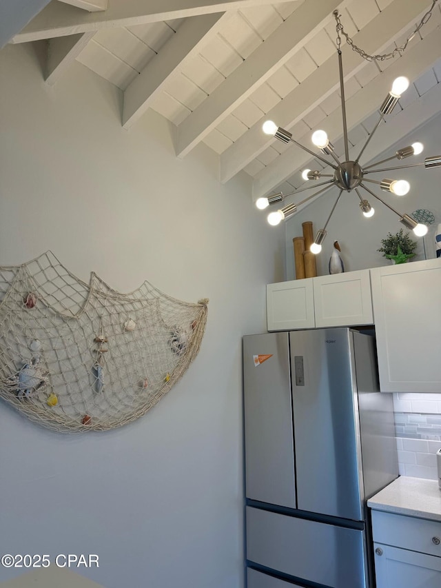 kitchen featuring visible vents, lofted ceiling with beams, freestanding refrigerator, white cabinets, and backsplash