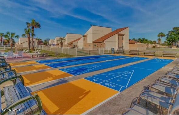 view of property's community featuring shuffleboard and fence