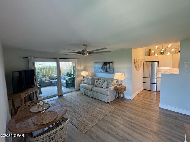 living area featuring wood finished floors, baseboards, and ceiling fan