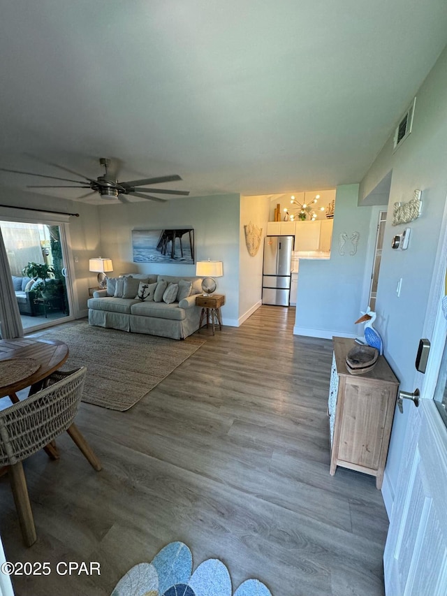 living area with visible vents, baseboards, wood finished floors, and a ceiling fan