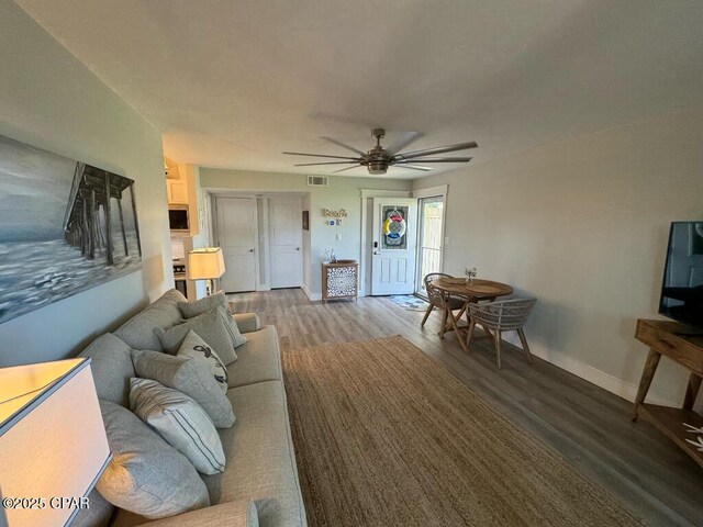 living room with ceiling fan and dark wood-type flooring