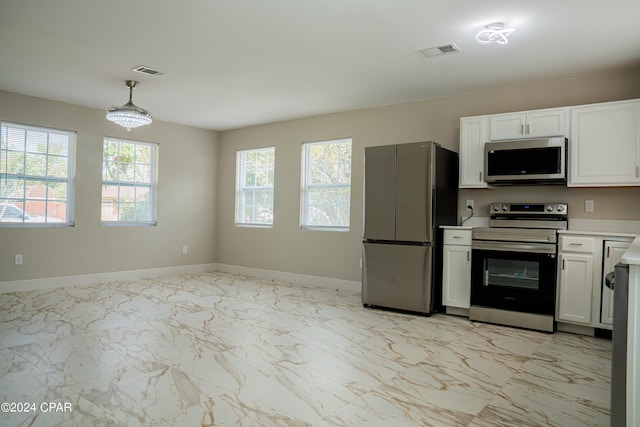 kitchen featuring hanging light fixtures, stainless steel appliances, and white cabinets