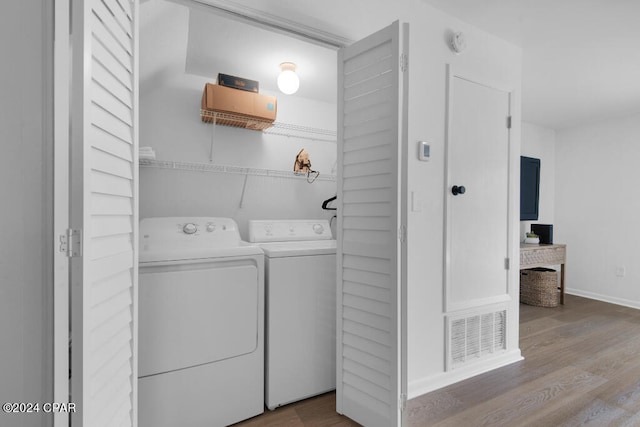 clothes washing area with washing machine and dryer and hardwood / wood-style flooring