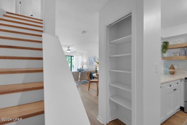 stairs with ceiling fan and light wood-type flooring