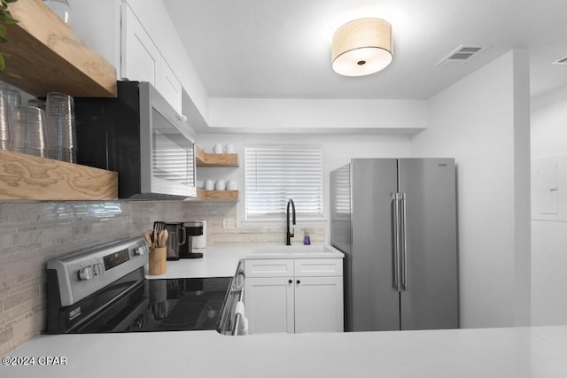 kitchen featuring appliances with stainless steel finishes, white cabinetry, tasteful backsplash, and sink