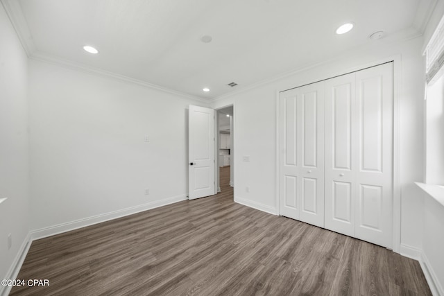 unfurnished bedroom featuring wood-type flooring, a closet, and ornamental molding