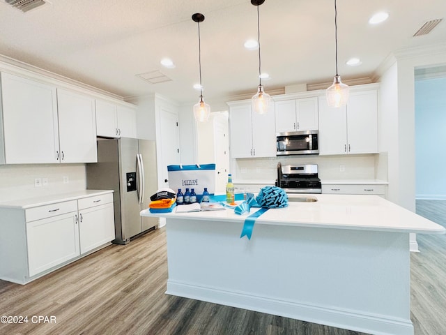 kitchen with decorative backsplash, stainless steel appliances, white cabinetry, and an island with sink