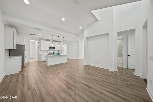 unfurnished living room with high vaulted ceiling and hardwood / wood-style flooring