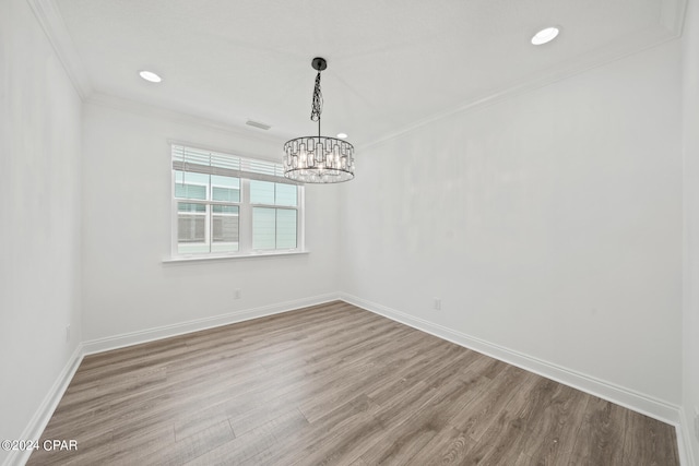 unfurnished room with an inviting chandelier, hardwood / wood-style flooring, and ornamental molding