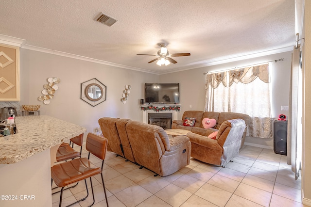 tiled living room with a textured ceiling, ceiling fan, and ornamental molding