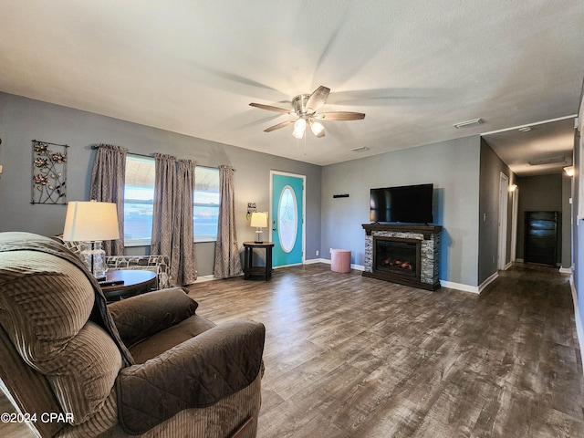 living room with a textured ceiling, hardwood / wood-style flooring, ceiling fan, and a fireplace