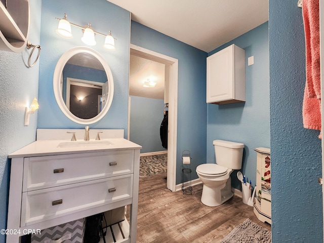 bathroom with toilet, vanity, and hardwood / wood-style flooring