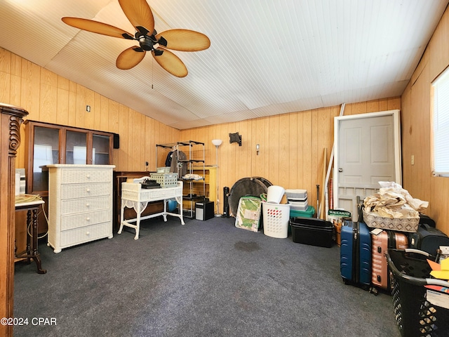 misc room with wood walls, ceiling fan, lofted ceiling, and dark carpet