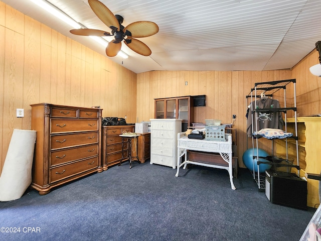 carpeted bedroom featuring lofted ceiling, ceiling fan, and wooden walls