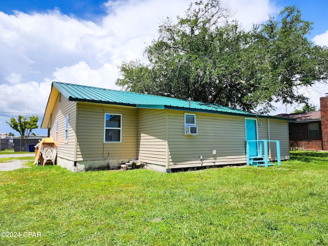 rear view of house featuring a lawn and cooling unit