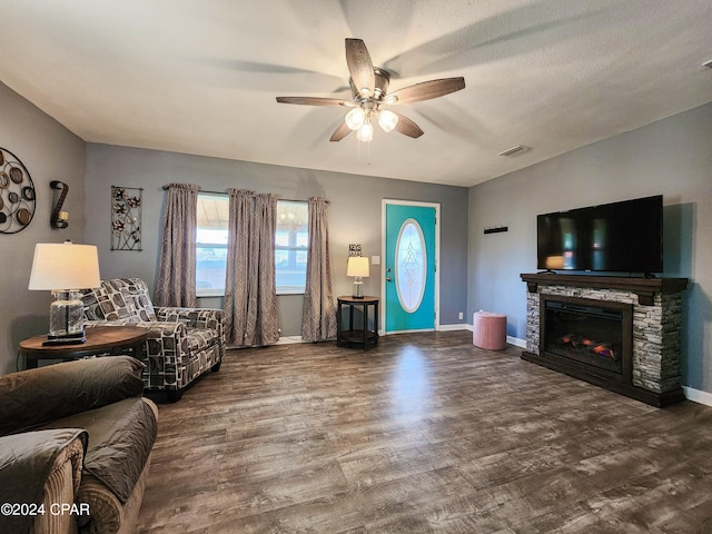 living room with ceiling fan, a textured ceiling, dark hardwood / wood-style floors, and a fireplace