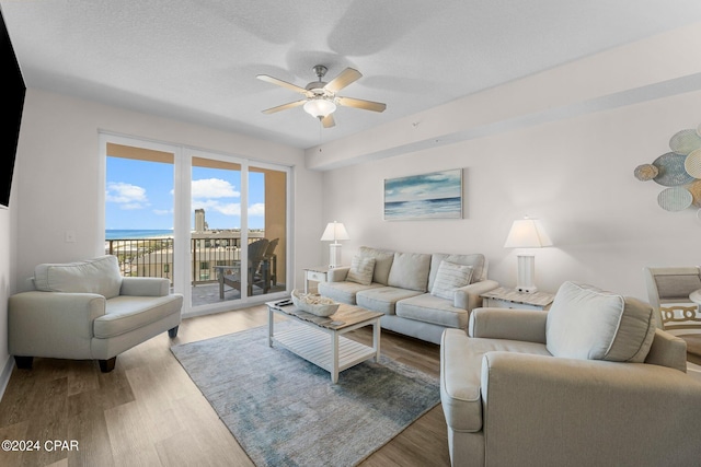 living room with ceiling fan, a water view, and hardwood / wood-style flooring