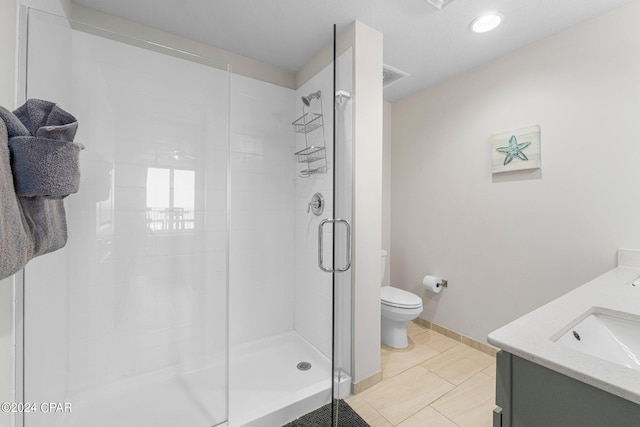 bathroom featuring tile patterned floors, vanity, a shower with door, and toilet