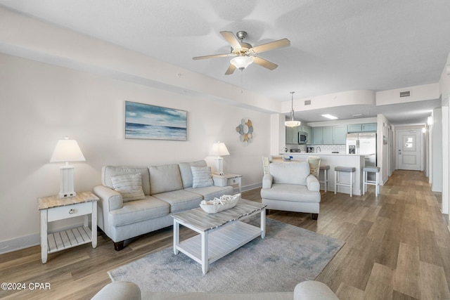 living room featuring ceiling fan and light hardwood / wood-style floors