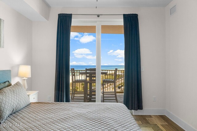 bedroom with access to exterior, a water view, and hardwood / wood-style floors