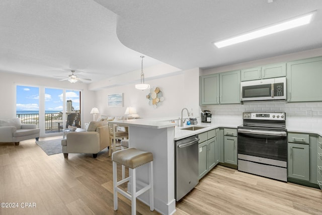 kitchen with stainless steel appliances, light hardwood / wood-style flooring, sink, and kitchen peninsula