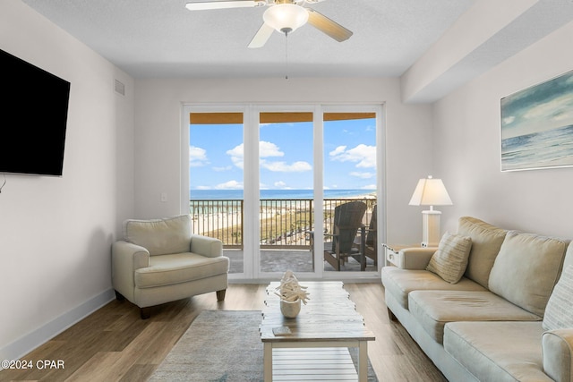 living room featuring a water view, hardwood / wood-style floors, and ceiling fan