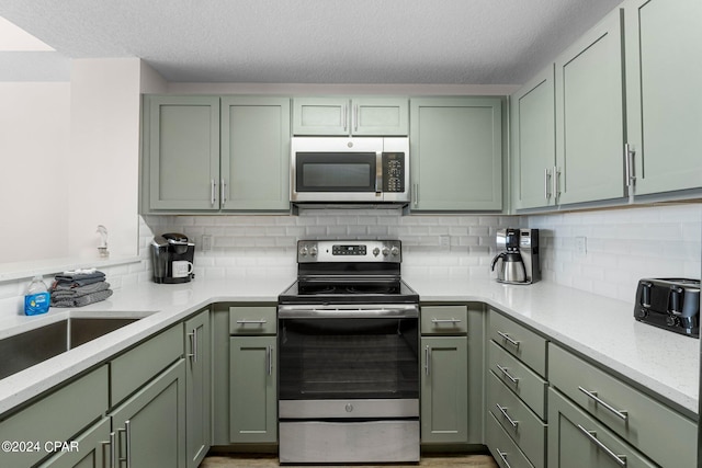 kitchen with green cabinets, decorative backsplash, and stainless steel appliances