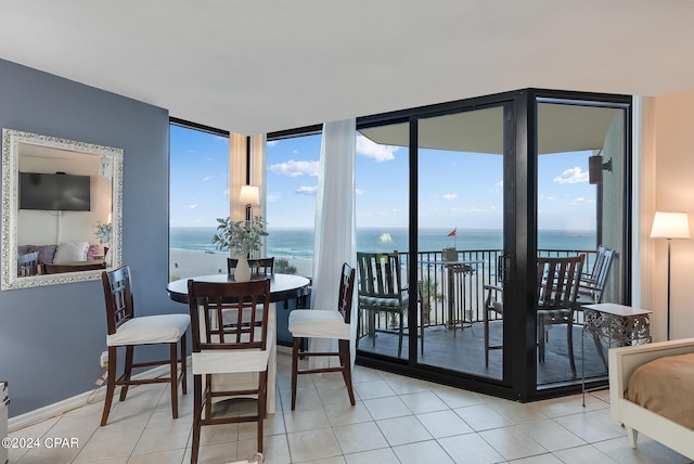 tiled dining room featuring a water view and floor to ceiling windows