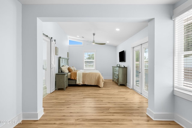 bedroom featuring lofted ceiling, a barn door, access to exterior, and light hardwood / wood-style flooring