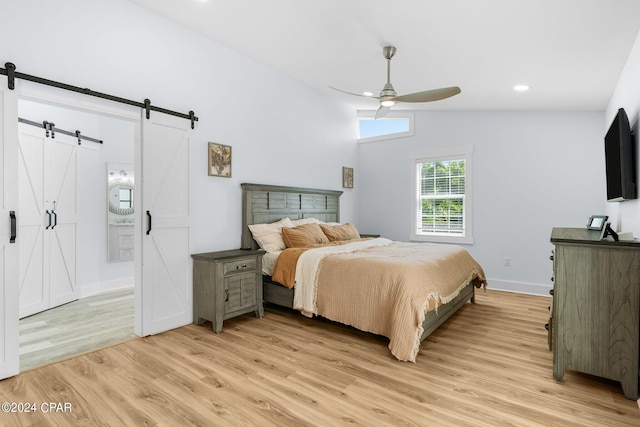 bedroom featuring vaulted ceiling, a barn door, ceiling fan, and light hardwood / wood-style floors