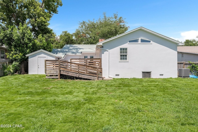 rear view of property with a wooden deck, central AC unit, a shed, and a lawn