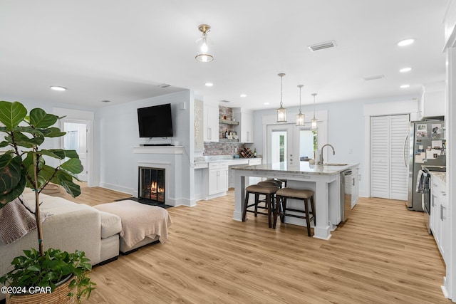 kitchen featuring pendant lighting, sink, a breakfast bar, a kitchen island with sink, and white cabinets