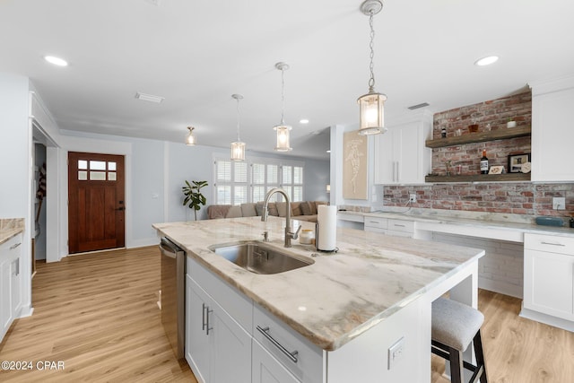 kitchen with white cabinetry, a kitchen bar, a kitchen island with sink, and sink