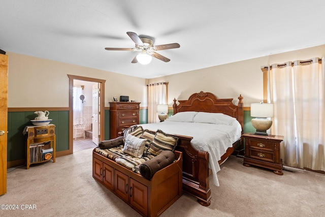 bedroom with ceiling fan, connected bathroom, and light colored carpet