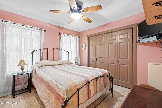 bedroom with light tile patterned flooring, ceiling fan, and a closet