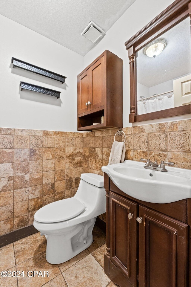 bathroom featuring toilet, tile walls, a textured ceiling, vanity, and backsplash