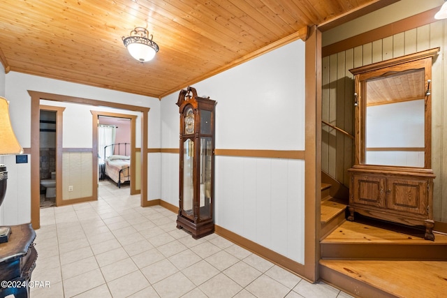 hallway with wood ceiling, ornamental molding, and light tile patterned floors