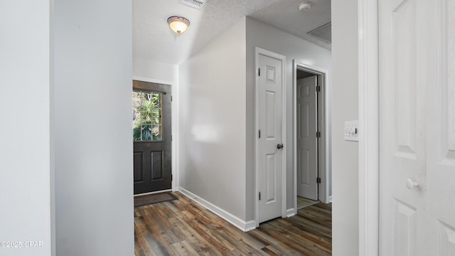 entrance foyer with dark wood-style floors, baseboards, and a textured ceiling